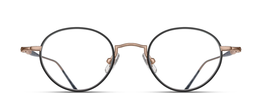A round, metal optical glasses frame with clear nose pads is pictured in a frontal view. The rim wire is is a light black color. The temples and nose-bridge is a matte rose gold color. 