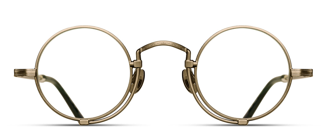 A gold optical glasses frame is pictured. The glasses have a round lens shape and feature an engraving along the rim wire.