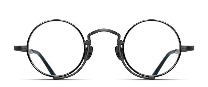 Optical glasses frames are pictured, displaying a frontal view. The glasses feature a round lens shape outlined in black and a M + N engraving along the rim wire.
