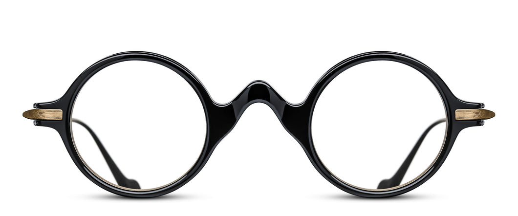 A black acetate / plastic optical frame is displayed. The frame features a round lens shape and a curved nose bridge. The hinges and temples of the frame are a gold color.